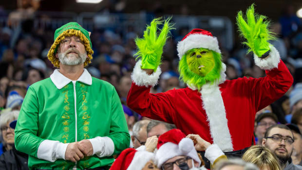 Two fans dressed up as the Grinch and an Elf stand in the stadium